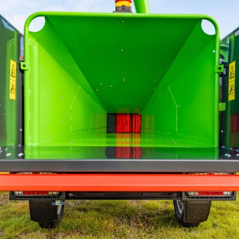 Arborist 150 6″ Road Towed Wood Chipper-2 Close-up of the Arborist 150 6″ Road Towed Wood Chipper interior, available from tool hire Newry, showing warning labels on both sides and grass beneath the machine.