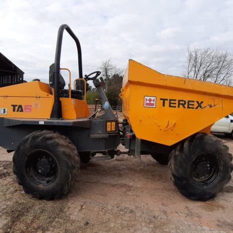 Terex TA6T Dumper A Terex TA6T Dumper with large black tyres, available from Tool Hire Newry, is parked on dirt beside a building and a white vehicle.
