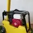 A Cargo PB60 5.5hp Vibrating Wacker Plate with a red engine, available for tool hire Newry, is shown on artificial grass indoors, beside a white wall and power socket.