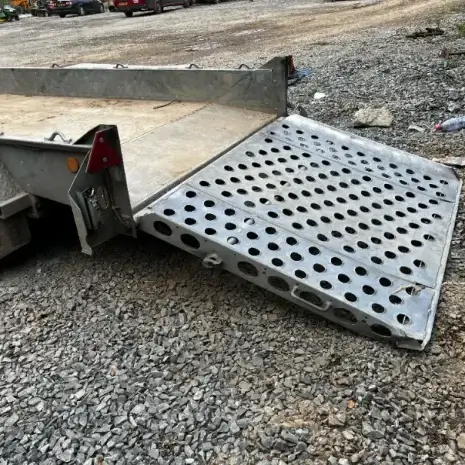 IFor Williams Plant Trailer-3 An IFor Williams Plant Trailer with a perforated loading ramp is parked on gravel at a tool hire location in Newry, with its ramp lowered to the ground.