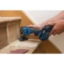 Someone sands the edge of a wooden stair tread using a Draper Storm Force® 20V Oscillating Multi-Tool (Sold Bare); sanding pads are nearby—perfect for anyone seeking tool hire in Newry for woodworking projects.