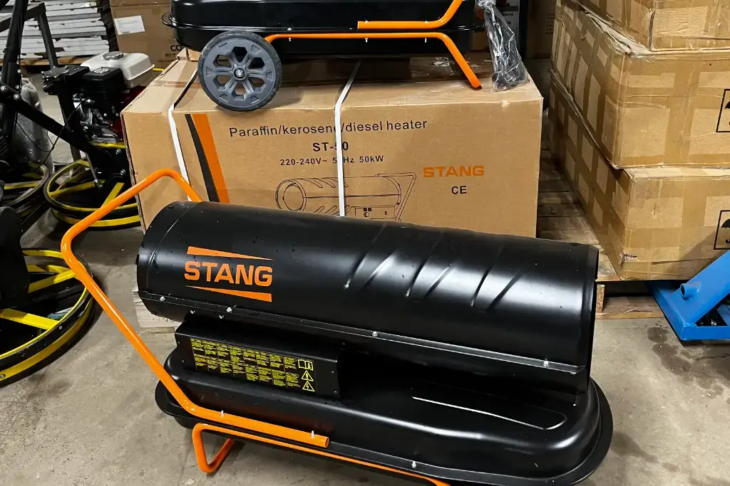 A black STANG paraffin kerosene diesel heater is placed in front of its cardboard box packaging in a warehouse setting, available for tool hire Newry customers seeking efficient heating solutions.