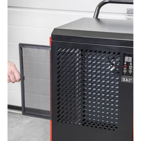 Sealey 70L Industrial Dehumidifier SDH70-3 A person removes the mesh filter from a black Sealey 70L Industrial Dehumidifier SDH70, revealing its control panel and ventilation grille—ideal equipment for tool hire Newry.