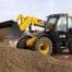 A yellow 531-70 telehandler from tool hire Newry moves a pile of gravel at a building site, with buildings visible in the background.
